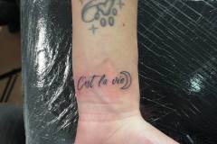 Piccolo lettering tattoo sul polso: "C'est la vie"